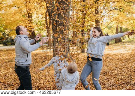 Portrait Of A Happy Beautiful Family Having Fun And Throwing Autumn Leaves In The Air. Happy Family,
