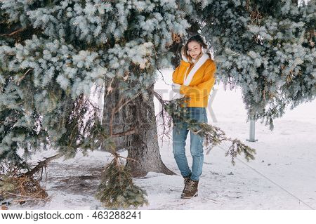Teen Blonde In A Yellow Sweater Outside In Winter. A Teenage Girl On A Walk In Winter Clothes In A S