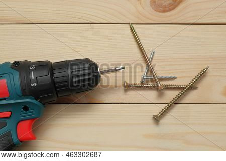 Table With Tool. Electric Screwdriver On A Wooden Table. Side View Of The Black Metallic Screws, Ele