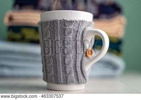 Stack Of Folded Woolen Checked Blankets And Mug In Wollen Cover, Autumn And Cold Winter Concept
