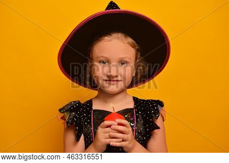 Cute Little Wizard Girl Wearing Witch Costume For Halloween Holding Red Burning Candle And Looking A
