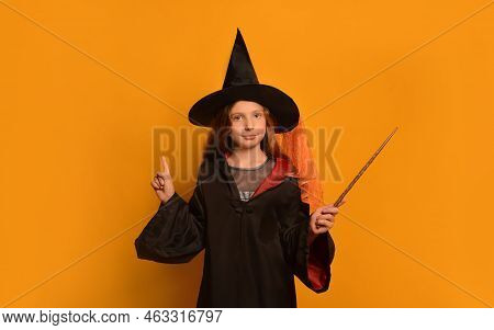 Cute Pre-teen Girl In Wizard Student Costume Holding Magic Wand, Looking At Camera And Holding Finge