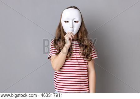 Portrait Of Anonymous Unknown Little Girl Wearing Striped T-shirt Covering Her Face With White Mask,