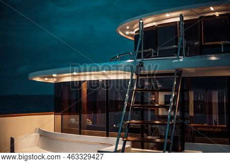 A Night Low-key Shot Of A Luxury Diving Safari Yacht Deck Lit By Multiple Ceiling Lamps, With A Ladd