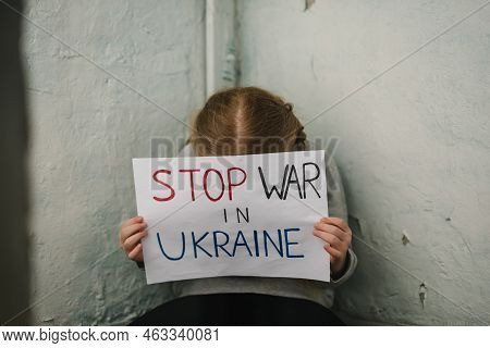 Poor Girl Protesting War Conflict Raises Banner With Inscription Stop War In Ukraine. Kid Sits Near 