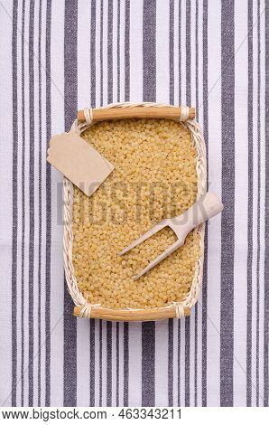Traditional Dry Pearl Couscous In A Wicker Basket On A Textile Background. Top View.