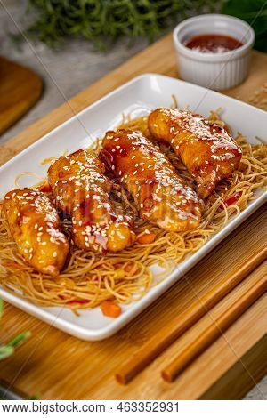 Crispy Chicken Tenders Are Coated In A Sweet, Spicy Sauce Served With Noodles