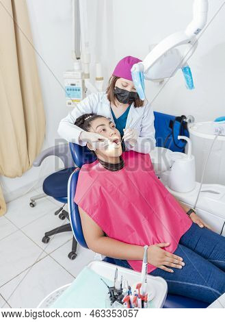 Dentist In His Office Examining Female Patient's Mouth. Female Dentist Examining Mouth To Teen Girl