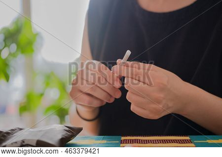 An Unrecognizable Person Making A Tobacco Cigarette At Home