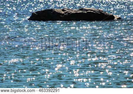 Sunlight Reflecting On Waves With A Small Rock Island In The Middle Of An Alpine Lake Taken In Castl