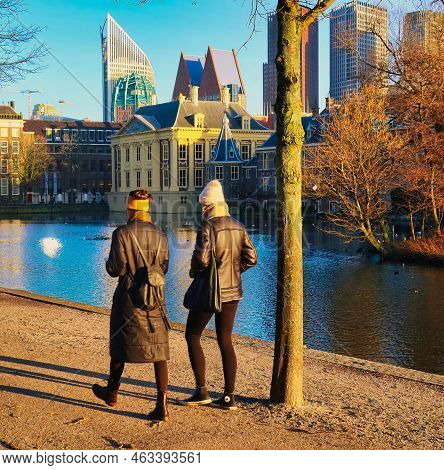 Den Haag, Netherlands - January 10 2022: Two Women Are Walking In The Cold Winter Sun Wearing Coats 