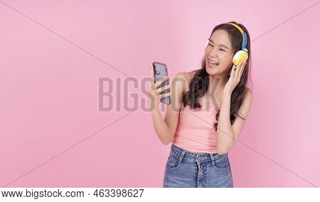 Charming Asian Woman Wear Headphones Holding Mobile Phone Listen Music Song Mood Enjoy On Pink Backg