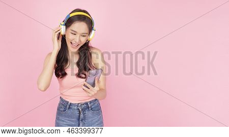 Charming Asian Woman Wear Headphones Holding Mobile Phone Listen Music Song Mood Enjoy On Pink Backg