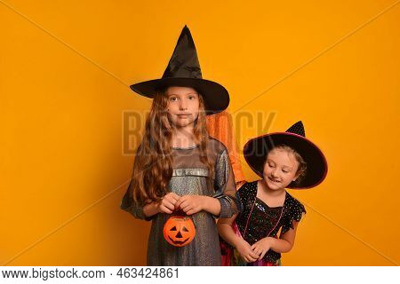 Two Cute Girls Sisters Dressed Up As Halloween Witches Or Wizards On A Yellow Background.

Kids In C