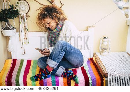 Cheerful Happy Woman Sit Down At Home On A Bench Outdoor Terrace Reading And Using Modern Phone For 