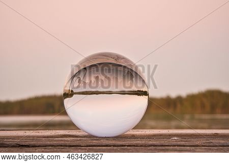 Glass Ball On A Wooden Pier At A Swedish Lake At Evening Hour. Nature Shot From Scandinavia