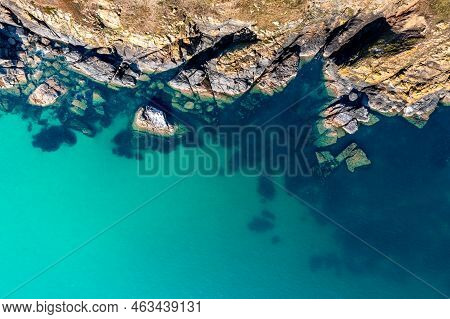 Aerial View Directly Above Rugged Rocky Outcrop Of Land Jutting Into An Emerald Green Ocean With San