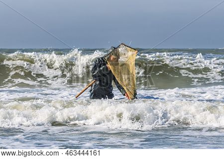 Amber Catching In The Baltic Sea. Amber Catcher Or Fisherman With Fisherman\'s Coat And Boots Into T