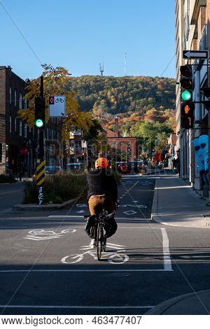 Montreal, Canada - 11 October 2022: Man Riding Bike On Rachel Street With Mount Royal In Background,