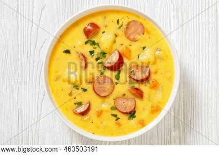 Kartoffelsuppe, German Potato Soup With Sausages In White Bowl On White Wooden Table, Horizontal Vie