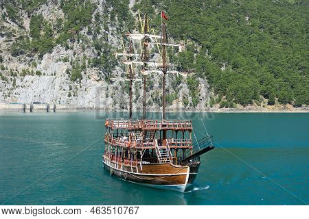 A Three-masted Tourist Yacht Floats On A Lake Among Mountain Cliffs Near The Oymapinar Dam. Green Ca