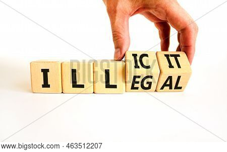Illegal Or Illicit Symbol. Businessman Turns Wooden Cubes And Changes The Concept Word Illegal To Il