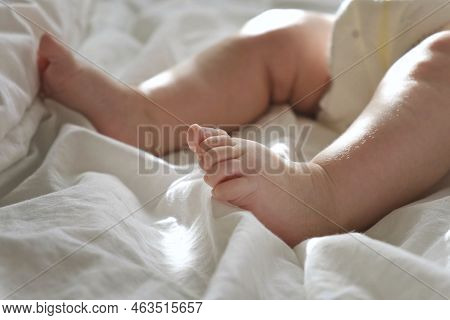 Baby Legs Close Up On White Blanket. Healthy Newborn Feet. Warm Sunlight. Beautiful Shot Of Infants 