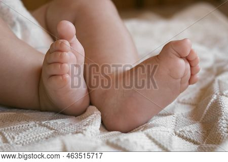Baby Legs Close Up On White Blanket. Healthy Newborn Feet. Warm Sunlight. Beautiful Shot Of Infants 