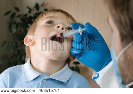 Kid Getting Polio Drops. Doctor Making To Child Oral Vaccination Against Infection. Little Blonde Ha