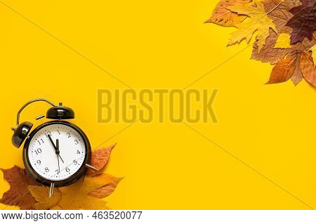 Daylight Saving Day. Fall Back. Black Alarm Clock And Autumn Leaves On Yellow Background. Daylight S