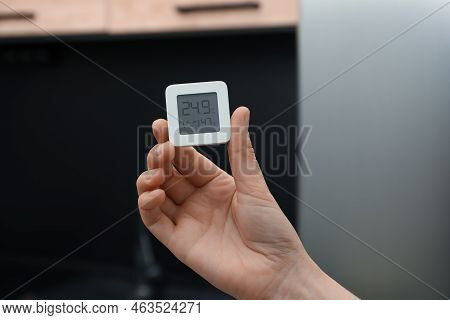 Woman Holding Digital Hygrometer With Thermometer At Home, Closeup