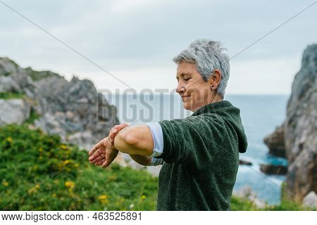Older Woman With Gray Hair, Wearing Sportswear, Looking At Her Sports Activity Marks As Well As Her 