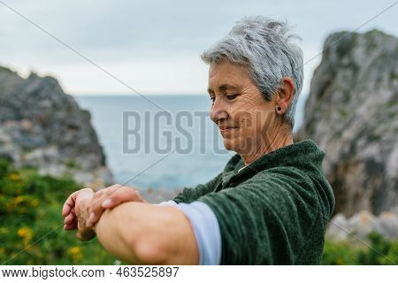 Older Woman With Gray Hair, Wearing Sportswear, Looking At Her Sports Activity Marks As Well As Her 