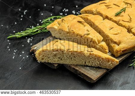 Homemade Italian Focaccia Modenese, With Rosemary And Olive Oil On A Wooden Board. Food Recipe Backg