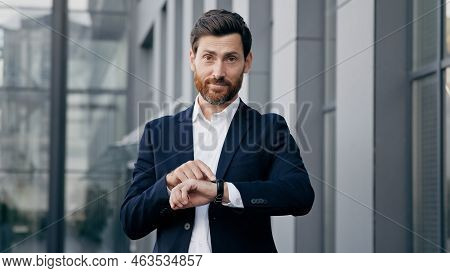 Professional Confident Businessman Standing Outdoors Waiting For Meeting Looks At Wristwatch Checkin