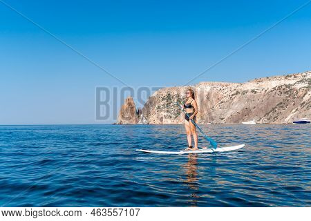 Sporty Girl On A Glanders Surfboard In The Sea On A Sunny Summer Day. Summer Activities By The Sea
