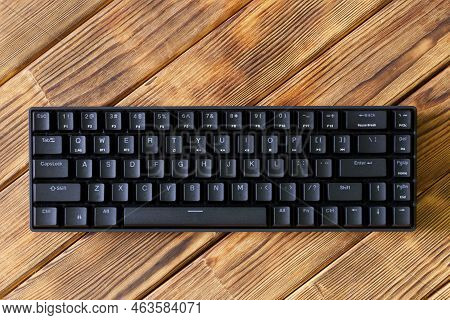 Small Compact Black Gaming Computer Keyboard On A Table Made Of Wooden Pine Boards. Wireless Keyboar