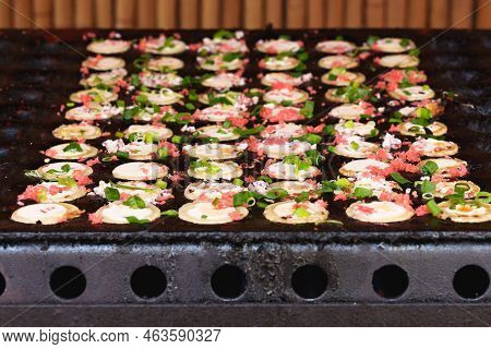 Japanese Street Food Takoyaki At Special Grill Pan. Process Of Cooking Takoyaki Balls With Octopus F