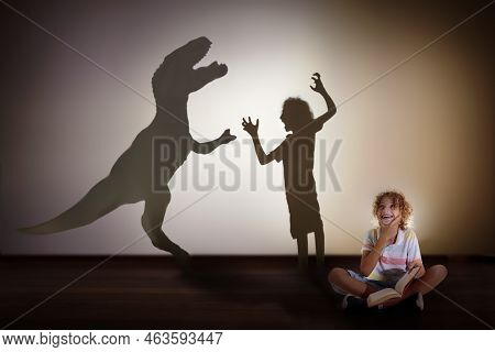 Dinosaur Shadow In Child Dream. Kids Read Book And Imagine Future. Little Boy Dreaming To Become A P