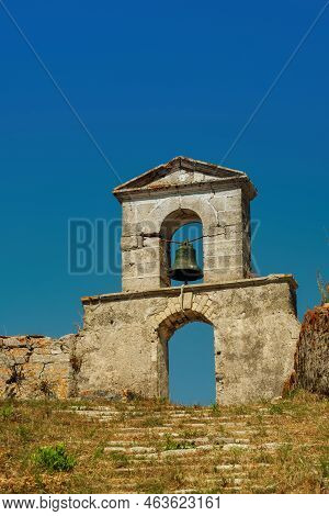 Decayed Stone Built Bell Tower With Hanging Bronze Bell On Top Of A Hill At The End Of A Stone Built