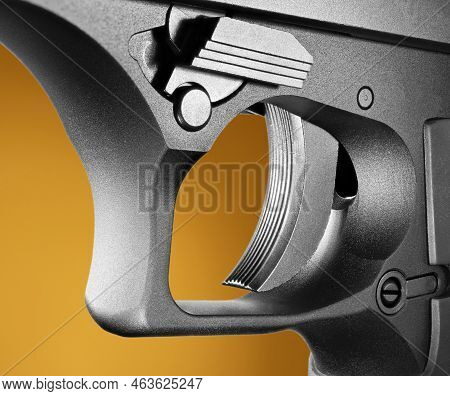 Closeup Of A Semi Automatic Pistol Trigger With An Orange And Brown Background