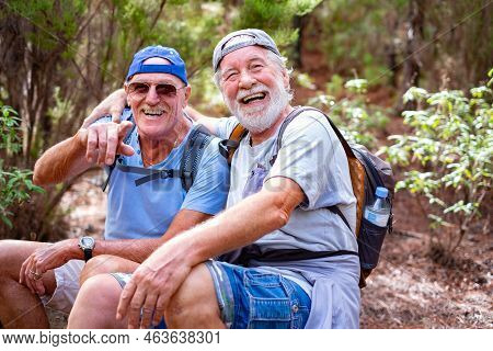 Cheerful Senior Couple Of Friends In Mountain Excursion Looking At Camera Laughing While Sitting To 