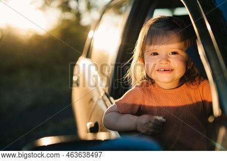 Baby Girl Looking Out Of The Car Window, Traveling For Holidays, Looking At Sunset From Car. Looking