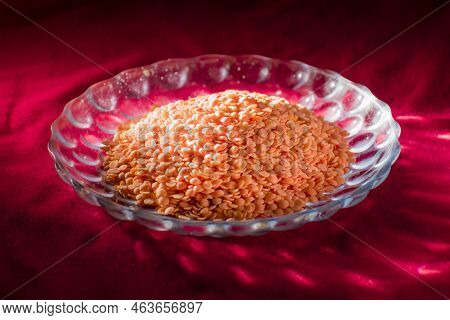Raw Uncooked Masur Dal Or Lentil On A Decorated Glass Plater Placed On Red Table Cloth