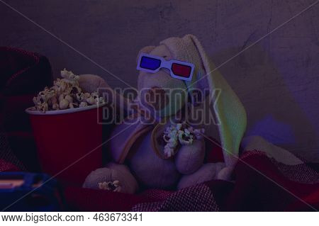 A Teddy Bear In 3d Glasses With In A Red Vat Of Popcorn Is Watching A Movie From A Dark Room. Soft F