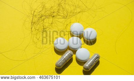 Pills And Fallen Hair On A Yellow Background. Baldness And Hair Loss Problem