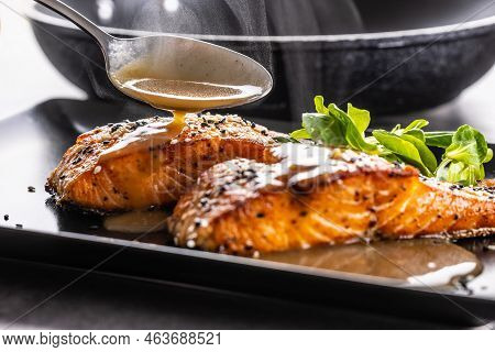 The Spoon Finishes The Portion By Pouring A Demiglas Sauce Over The Salmon Fillets.
