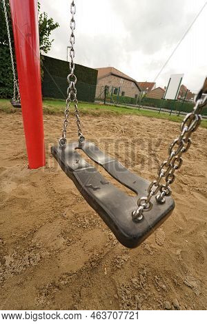 Colorful Vertical Wide Anlge Closeup On An Empty Black Swingset With Chains And Red Pole In A Desert
