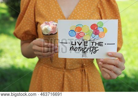 Woman Holding Card With Phrase Live The Moments And Ice Cream Outdoors, Closeup