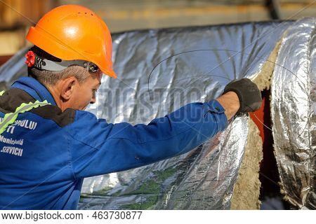 Bucharest, Romania - October 13, 2022: Worker Uses Glass Wool To Thermal Insulate A Hot Water Metall